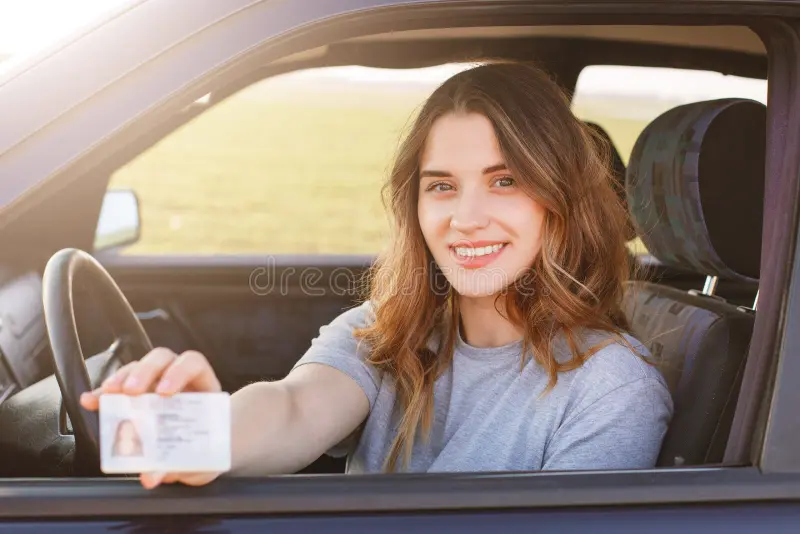 smiling-young-female-pleasant-appearance-shows-proudly-her-drivers-license-sits-new-car-being-inexperienced-driver-looks-115924098